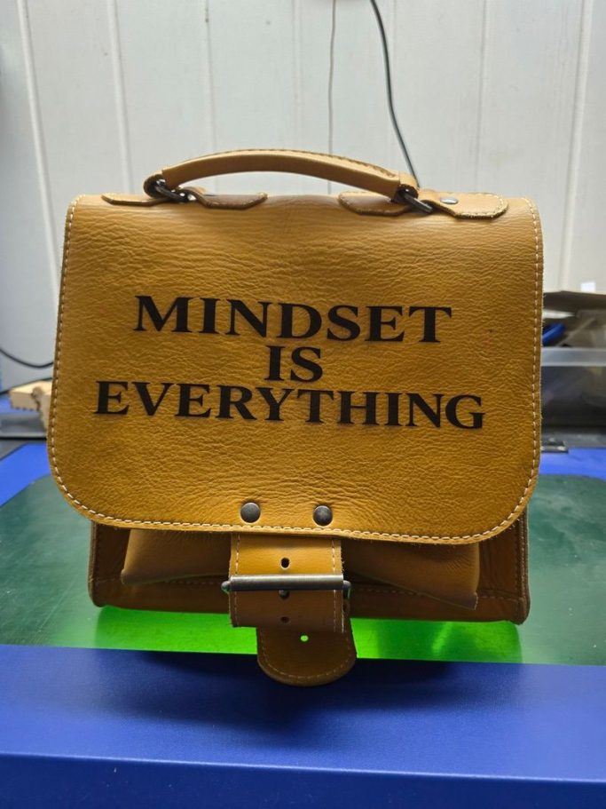 Ledertasche mit individueller Lasergravur Lasergravur auf brauner Ledertasche mit Schriftzug Mindset Is Everything